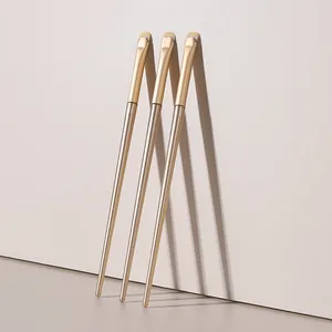Close-up detail of three crescent-shaped eyeshadow brushes with champagne gold handles