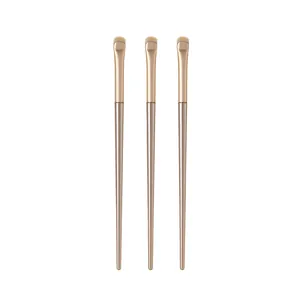 Macro view of three champagne gold crescent detail eyeshadow brushes for makeup.