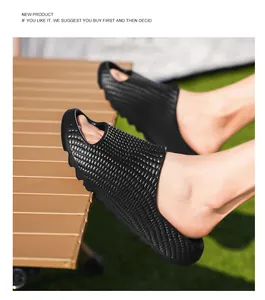 Macro view of black textured thick-sole slides worn outdoors on green grass.