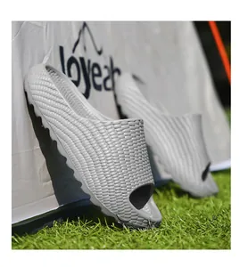Close-up side view of grey thick-soled beach slides with corn-textured design on grass