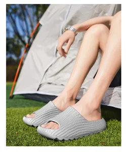 Close-up detail of textured grey outdoor slides worn next to a camping tent on grass