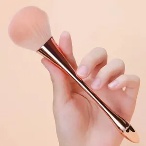 Primer plano de un pincel para polvo de uñas rosa con mango metálico de oro rosa