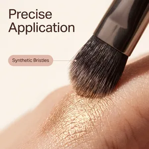 Detalle de brocha para sombra de ojos con cerdas sintéticas aplicando maquillaje dorado.