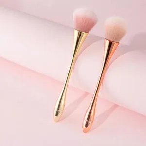 Primer plano de pinceles de uñas rosa suave con mangos metálicos en oro y oro rosa
