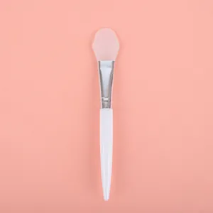 Detailed view of a professional pink silicone mask brush with a sleek white handle