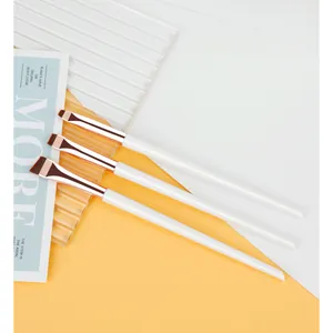 Detail of three angled eye makeup brushes with white handles and rose gold ferrules