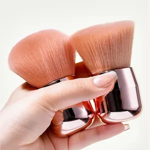 Close-up view of a soft pink mushroom head loose powder brush with rose gold handle