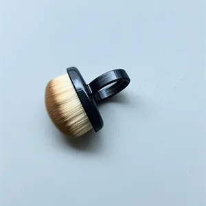 Primer plano de un cepillo para uñas negro con anillo y cerdas suaves marrones y beige