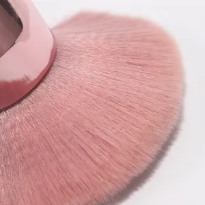 Primer plano de las suaves cerdas rosadas de una brocha de maquillaje tipo hongo.