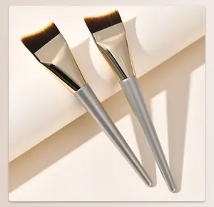 Close-up of two professional ultra-thin moon-shaped foundation brushes with silver handles.