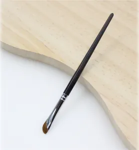 Close-up of professional angled eyeliner brush with fine bristles on wood background