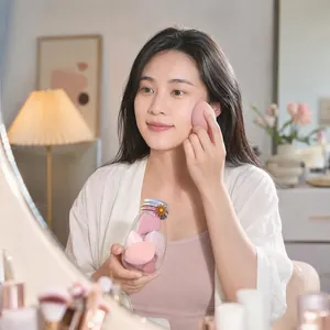 Detail shot of a woman using a pink makeup sponge blender from a milk bottle container