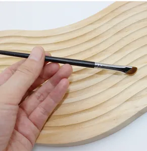 Detailed close-up of a professional angled sickle eyeliner brush held by hand.