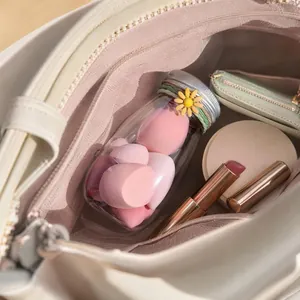 Detail of pink beauty sponges in a portable milk bottle container inside a handbag