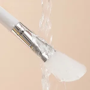 Silicone face mask brush with soft head mud mask applicator being rinsed under running water