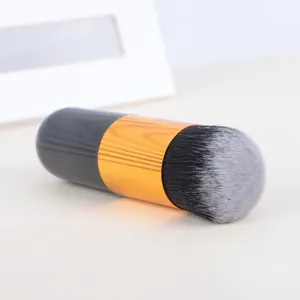 Detailed view of a portable chubby makeup brush with gold ferrule and grey bristles.