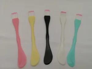 Close-up of dual-ended facial mask brushes with soft bristles and plastic spatula
