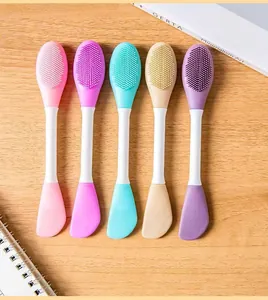 Close-up detail of five colorful double-ended silicone facial mask brushes on wood background.