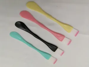 Detailed view of dual-ended facial mask brushes featuring spatulas and soft pink-tipped bristles