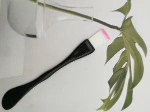 Detail of dual-use facial mask brush with soft pink-tipped bristles and flat spatula handle