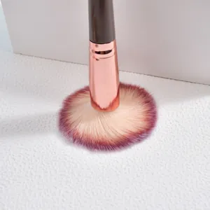 Détail en gros plan des poils dégradés doux et de la virole or rose d'un pinceau de maquillage
