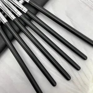 Detalle en primer plano de los largos mangos de brochas de maquillaje negro mate y virolas