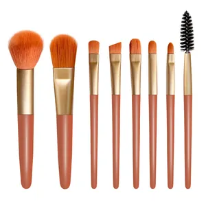 Primer plano de 8 brochas de maquillaje profesionales con cerdas naranjas en fondo blanco