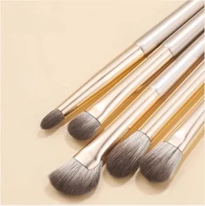 Close-up detail showing soft synthetic grey bristles and gold ferrules of makeup brushes.