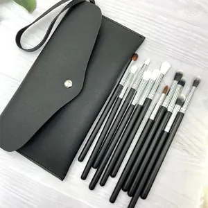 Detailed view of 11 professional makeup brushes with soft fiber hair and black leather pouch.
