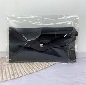 A black faux leather makeup brush pouch packaged in a transparent protective plastic bag