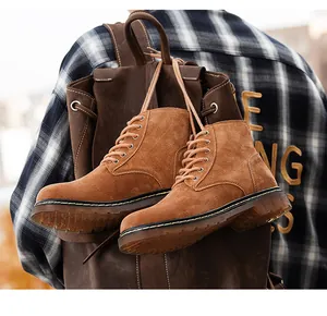 Détail de bottines Martin en daim marron à lacets suspendues à un sac à dos