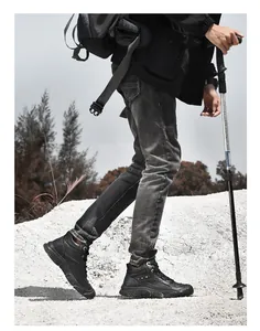 Detail shot of black genuine leather hiking boots worn in a rugged outdoor landscape