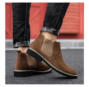 Close-up side view of brown suede men's Chelsea boots styled with denim on the pavement
