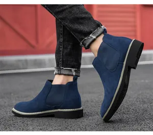 Detailed side view of men's blue suede Chelsea boots worn on pavement outdoors