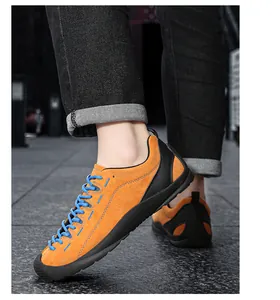 Vue détaillée de baskets décontractées en daim orange avec lacets bleus portées en extérieur