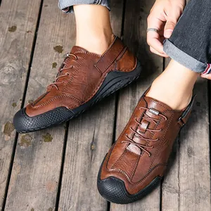 Braune handgefertigte Freizeit-Lederschuhe für Herren mit feinen Nähten auf Holz
