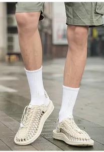 Vista dettagliata dei sandali intrecciati beige da uomo con calzini bianchi