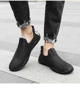 Κοντινό πλάνο μαύρων ανδρικών slip-on παπουτσιών με τζιν με σκισίματα