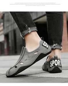 Vue rapprochée de chaussures décontractées en cuir gris ajouré et respirant pour hommes aux pieds.