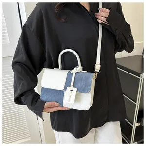 Vue détaillée d'un sac bandoulière bicolore porté avec une tenue moderne