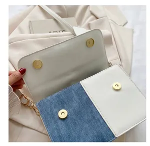 Gros plan des fermoirs magnétiques dorés sur un sac en patchwork de denim et cuir.