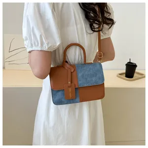 Élégant sac à main en patchwork de denim et cuir porté par un mannequin en robe blanche
