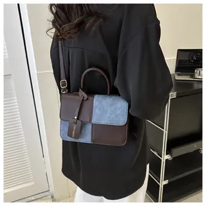 Vue détaillée d'un sac à bandoulière en patchwork de cuir marron et de denim bleu