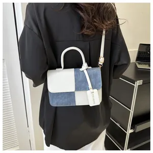 Vue arrière élégante d'un sac bandoulière en patchwork bleu denim et cuir blanc de qualité