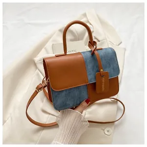 Détail d'un sac à main chic bicolore en similicuir marron et denim bleu de qualité