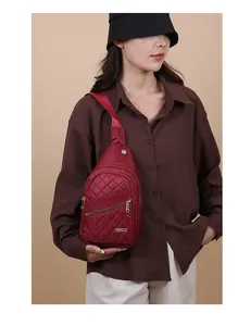 Woman wearing a burgundy quilted sling chest bag with multiple zipper pockets
