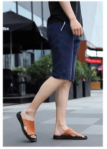 Side view detail of men's brown slip-on sandals with textured finish and navy shorts