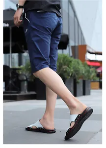 Walking shot of men's white casual sandals featuring non-slip soles and metal stud details.