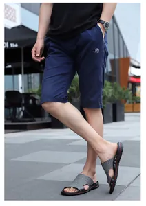 Detail view of men's casual slide sandals with grey crocodile pattern on an outdoor model