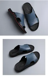 Detail view of men's casual slippers with blue crocodile pattern and metal studs.
